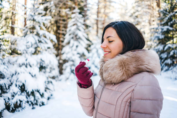 стокові фото, фото роялті-фрі та зображення на тему застосування бальзаму для губ на снігу - a person applying makeup in winter.